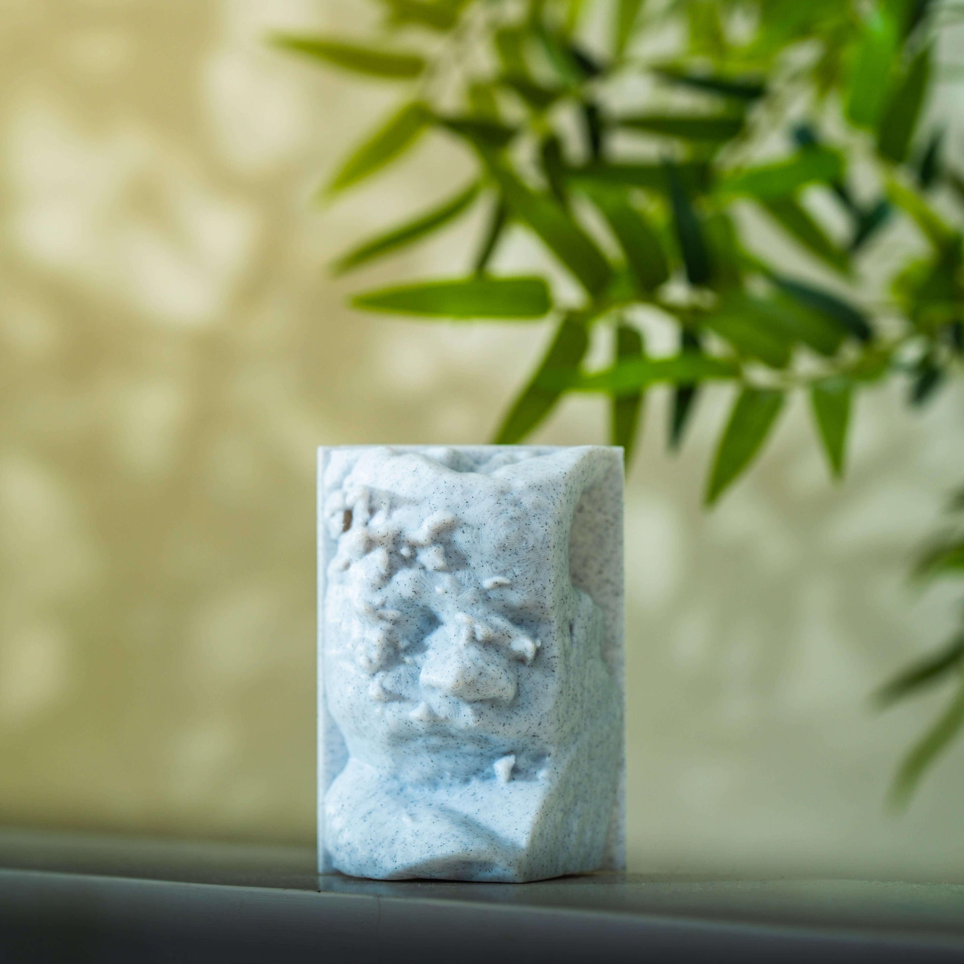 Scultura di Vedo in 3d creata dall'ecografia appoggiata su un piano con sfondo verde e pianta di bambù